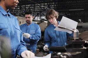 professionele teams van industriële arbeiders in veiligheidsuniformen en ingenieurspartners werkten met metaalbewerkingsgereedschap, bespraken mechanisch tekenen voor draaimachines en werkplaatsen in de productiefabriek. foto