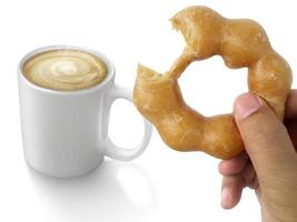 Donut in iemands hand en warme koffie geïsoleerd op een witte achtergrond foto