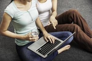 jonge vrouwen zitten en met behulp van laptop foto