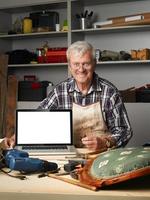 gepensioneerde timmerman met laptop foto