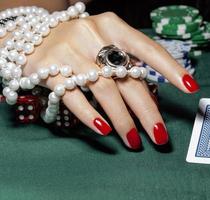 handen van jonge blanke vrouw met rode manicure in casino