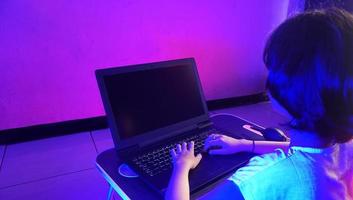 close-upbeeld van een klein meisje dat werkt en typt op het toetsenbord van een laptopcomputer foto