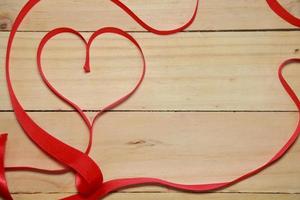 ontwerp rood hartvormige lint bewustzijn op oude leeftijd hout achtergrond. Valentijn concept. ruimte voor tekst. foto