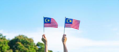 hand met vlag van Maleisië op blauwe hemelachtergrond. nationale feestdag september Maleisië en onafhankelijkheidsdag in augustus foto