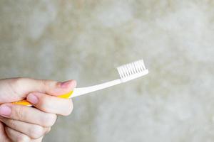 hand met tandenborstels in de badkamer. levensstijl, dagelijkse routine, werelddag voor mondgezondheid en gratis tandheelkundig dagconcept foto