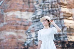 toeristische vrouw in witte jurk op bezoek aan oude stoepa in wat chaiwatthanaram tempel in ayutthaya historisch park, zomer, azië en thailand reisconcept foto