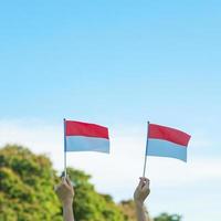 hand met de vlag van Indonesië op blauwe hemelachtergrond. onafhankelijkheidsdag van indonesië, nationale feestdag en gelukkige vieringsconcepten foto