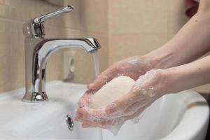 hygiëne. handen schoonmaken. handen wassen met zeep. vrouwenhand met schuim. bescherm jezelf tegen coronavirus covid-19 pandemie foto