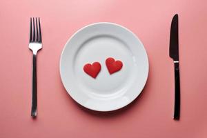 twee harten in bord met bestek. romantisch diner in restaurantconcept. ontmoeting van geliefden bij huwelijksreceptie. foto