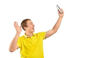 grappige kerel in fel geel t-shirt videochatten met behulp van videogesprek met telefoon, glimlachende jonge man foto
