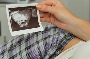 zwangere vrouw geniet van het kijken naar echografie van de baby foto