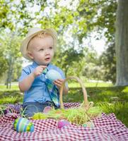 schattige kleine jongen genieten van zijn paaseieren buiten in park foto