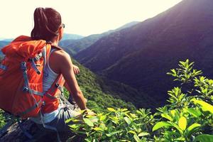 vrouw backpacker geniet van het uitzicht op de bergtop klif