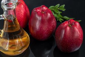 appelciderazijn en rode appels op een donkere, houten ondergrond. selectieve aandacht. gefermenteerd product. gezond eten. foto