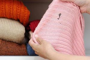 vrouw handen met gebreide doek met gat gemaakt door mot foto