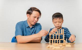 een jongen speelt thuis met zijn vader met een houten puzzel. foto