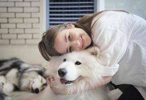 meisje huisdier eigenaar knuffelen met hond puppy. gelukkige menselijke vrouw en schattige grappige hond die samen op de vloer liggen foto