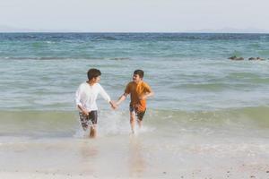 homoseksueel portret jonge aziatische paar lopen met vrolijk samen op het strand in de zomer, azië gay gaan toerisme voor vrije tijd en ontspannen met geluk in vakantie op zee, lgbt juridisch concept. foto