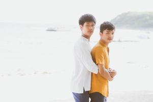 homoseksueel portret jong aziatisch paar staande knuffel samen op het strand in de zomer, azië homo gaand toerisme voor vrije tijd en ontspannen met romantisch en geluk in vakantie op zee, lgbt-concept. foto