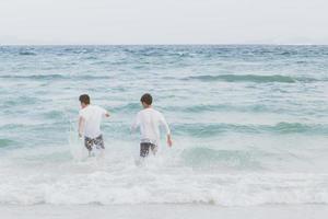 homoseksueel portret jonge aziatische paar lopen met vrolijk samen op het strand in de zomer, azië gay gaan toerisme voor vrije tijd en ontspannen met geluk in vakantie op zee, lgbt juridisch concept. foto