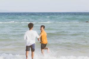 homoseksueel portret jonge aziatische paar lopen met vrolijk samen op het strand in de zomer, azië gay gaan toerisme voor vrije tijd en ontspannen met geluk in vakantie op zee, lgbt juridisch concept. foto