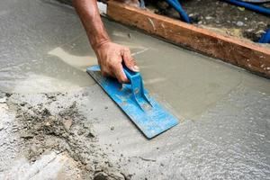 werknemer nivellering en afvlakking van beton op het repareren van straat. constructie concept foto