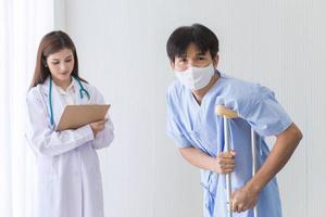 Aziatische vrouwelijke arts controleert het lopen van een mannelijke patiënt foto