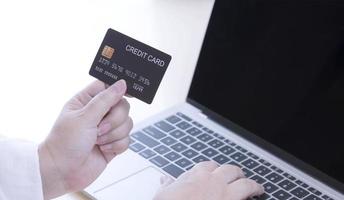 Overgewicht vrouw hand met creditcard mock-up en het gebruik van laptopcomputer op witte tafel in thuiskantoor foto