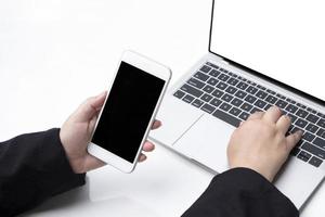 de hand van een dikke zakenvrouw die smartphone vasthoudt en laptop gebruikt om haar werk te doen op een witte tafel op kantoor foto