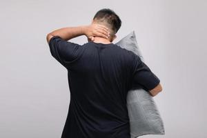 nekpijn concept, portret aziatische man met grijs kussen en moe of pijn in zijn nek. studio-opname geïsoleerd op grijs foto
