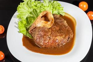 vleesschotel op een bord met saus. kipfilet, gebakken varkensvlees. peterselie. mosterdsaus en ketchup. op een donkere achtergrond. foto
