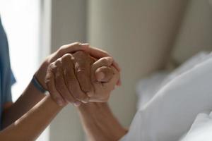 artsen houden elkaars hand vast en moedigen oudere patiënten aan die alleen zijn in de speciale kamer van het ziekenhuis. foto