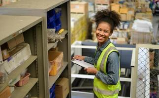 vrouwelijke magazijnmedewerker die artikelen telt in een industrieel magazijn op de tussenverdieping van de fabriek. dat is een opslag voor kleine en lichte elektronische onderdelen. foto