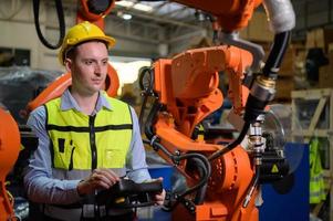 een mannelijke werknemer bestuurt een lasrobot. door gebruik te maken van dwanglassen met een controlescherm dat wordt gebruikt voor precisielascontrole. snel en zeer veilig foto