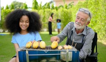 gezinsvakantie-activiteiten met opa, moeder en kinderen met camping. bbq grill en speel samen in de tuin gelukkig op vakantie. foto