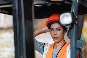 portret van een aziatische vrouw met een vorkheftruck die wordt gebruikt om zware voorwerpen in een magazijn op te tillen. foto