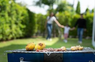 gezinsvakantie-activiteiten omvatten vader, moeder en kinderen met campingbarbecue en samen gelukkig spelen in de tuin op vakantie. foto