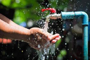 waterconcept in het dagelijks leven. handen ondersteunen het water dat uit de kraan stroomt. water dat uit de kraan spat foto