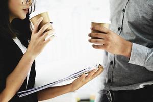 focus op de hand van een vrouw die een kopje koffie vasthoudt en praat met een collega tijdens de middagpauze. foto