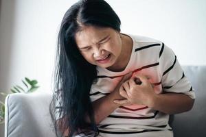 close-up van Aziatische vrouw met een hartaanval. vrouw die de borst aanraakt en pijn op de borst heeft. gezondheidszorg en medisch concept. foto