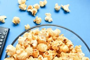 heerlijk karamel popcorns zoet dessert op blauwe achtergrond, snacks in een glazen kom voor favoriete filmtijden. foto