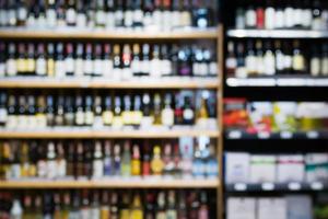 abstract vervagen wijnflessen op sterke drank alcohol planken in supermarkt achtergrond foto