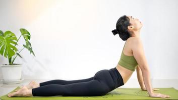 vrouw die yoga doet op de groene yogamat om thuis te mediteren en te oefenen. foto