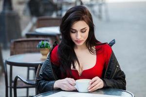 stijlvolle jongedame koffie drinken in een stad street.stylish hipster meisje koffie drinken in de straat. buitenshuis mode portret van jong mooi meisje koffie drinken. foto