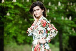 vrouwenportret met een haar dat in de wind beweegt. portret van jonge mooie Russische brunette meisje in zomer groen park. Europese blanke vrouw in jurk. foto