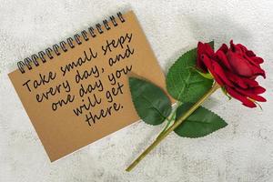 motiverende en inspirerende quote op bruin notitieboek met rode rozen op marmeren bureau foto