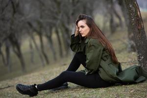 afbeelding van jonge mooie vrouw die regenjas draagt bij koud weer. denker europees meisje in de lente natuur. foto