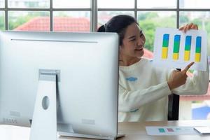 werk vanuit huis en online leer- of vergaderconcept. mooie jonge vrouwen die op de computer werken met behulp van een smartphone in de woonkamer of co-werkruimte. student studie online training. foto