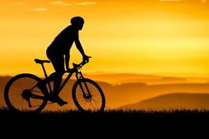 silhouetten van mountainbikes en fietsers in de avond gelukkig. reis- en fitnessconcept. silhouet van fietsers die 's avonds toeren fietsen concept foto