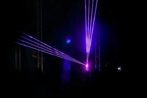 paarse laser neonstralen. menigte van mensen die kijken naar lasershow op straatfestival. foto